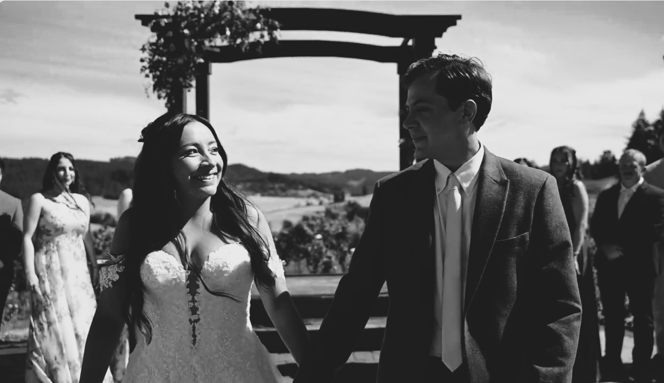 Newly married smile at each other as they walk back down aisle after their wedding ceremony.